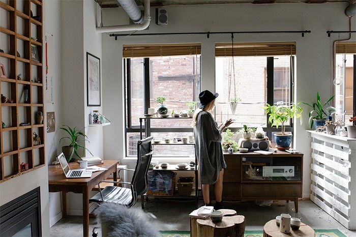 a woman standing, home-office, woman standing inside her home-office, a room with laptop, chair, plants
