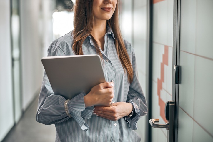 Calm employee dressed in a trendy shirt holding a laptop