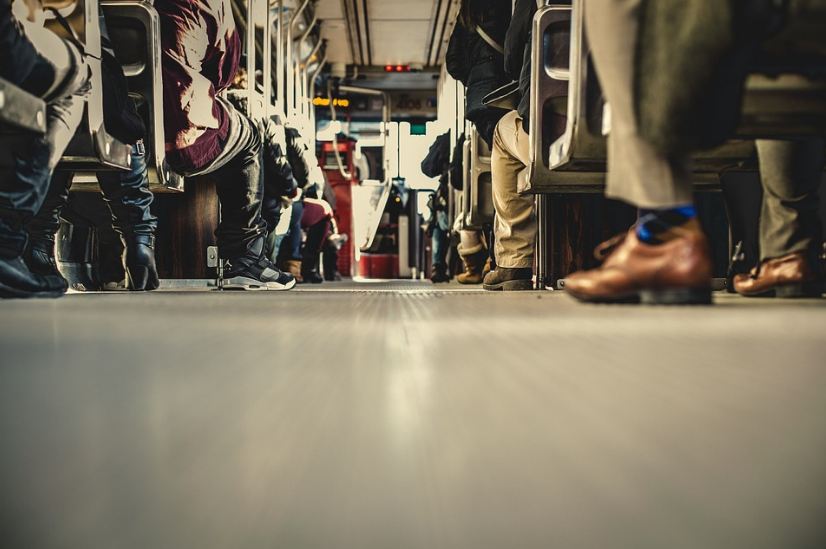 the inside of a full bus, commuters’ feet