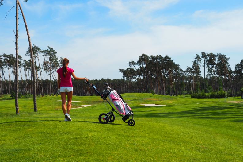 Woman walking at a golf course using a cart bag