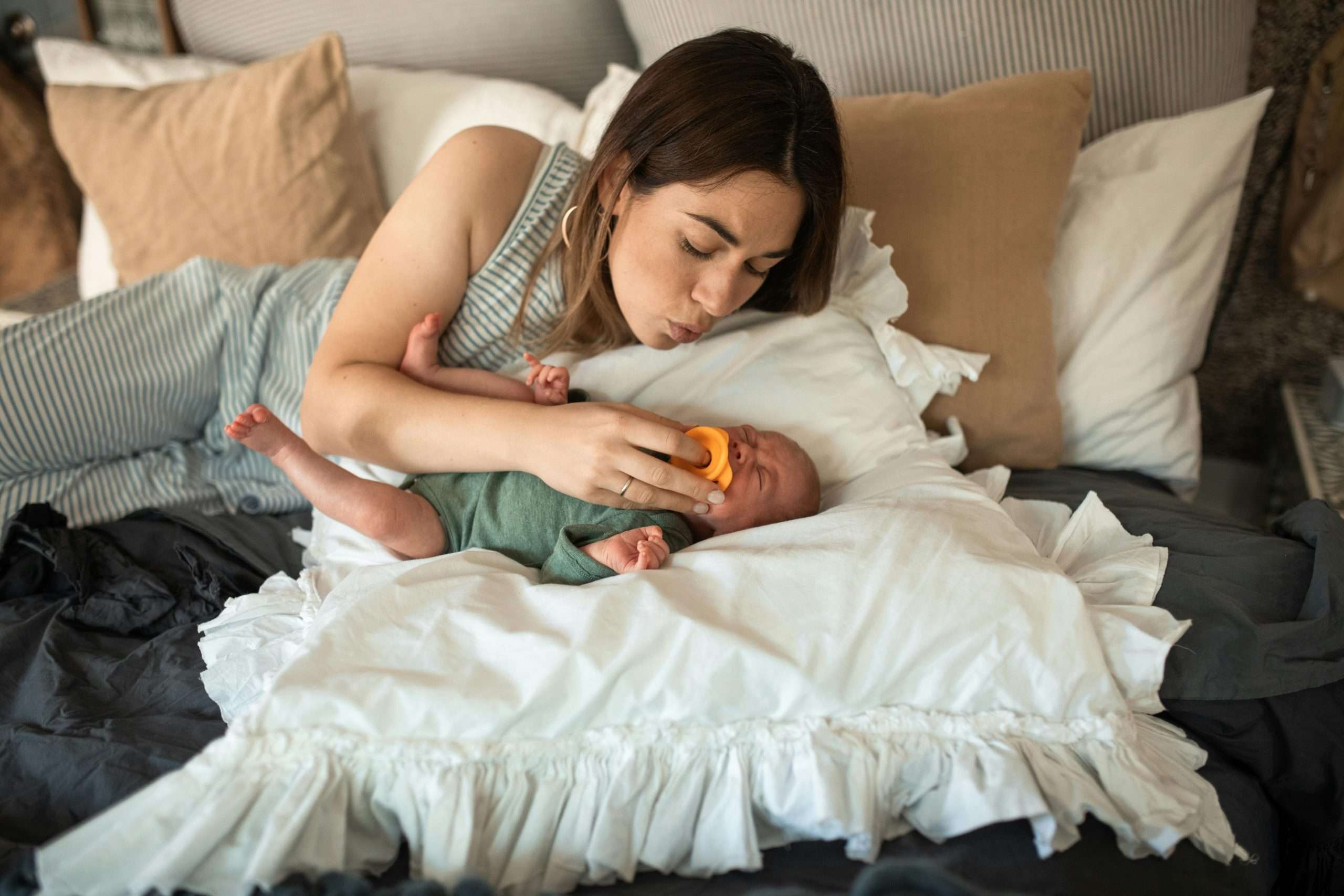 Mother putting pacifier on her baby's mouth