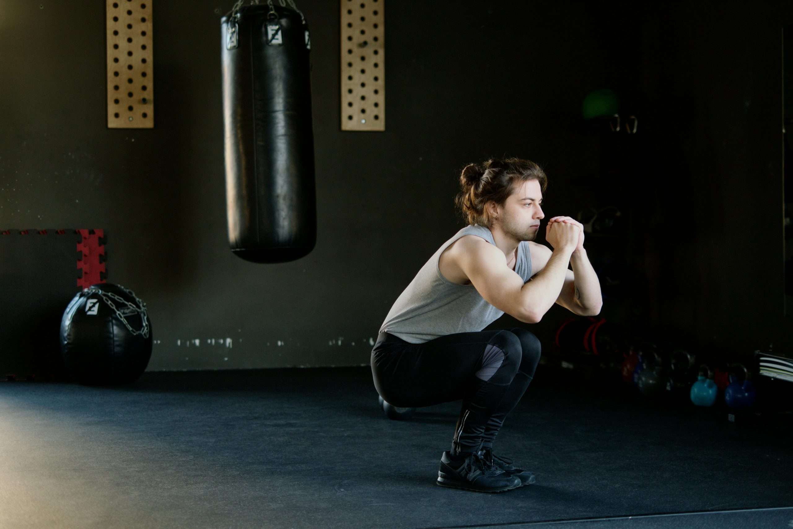 man in a gray tank top doing squats