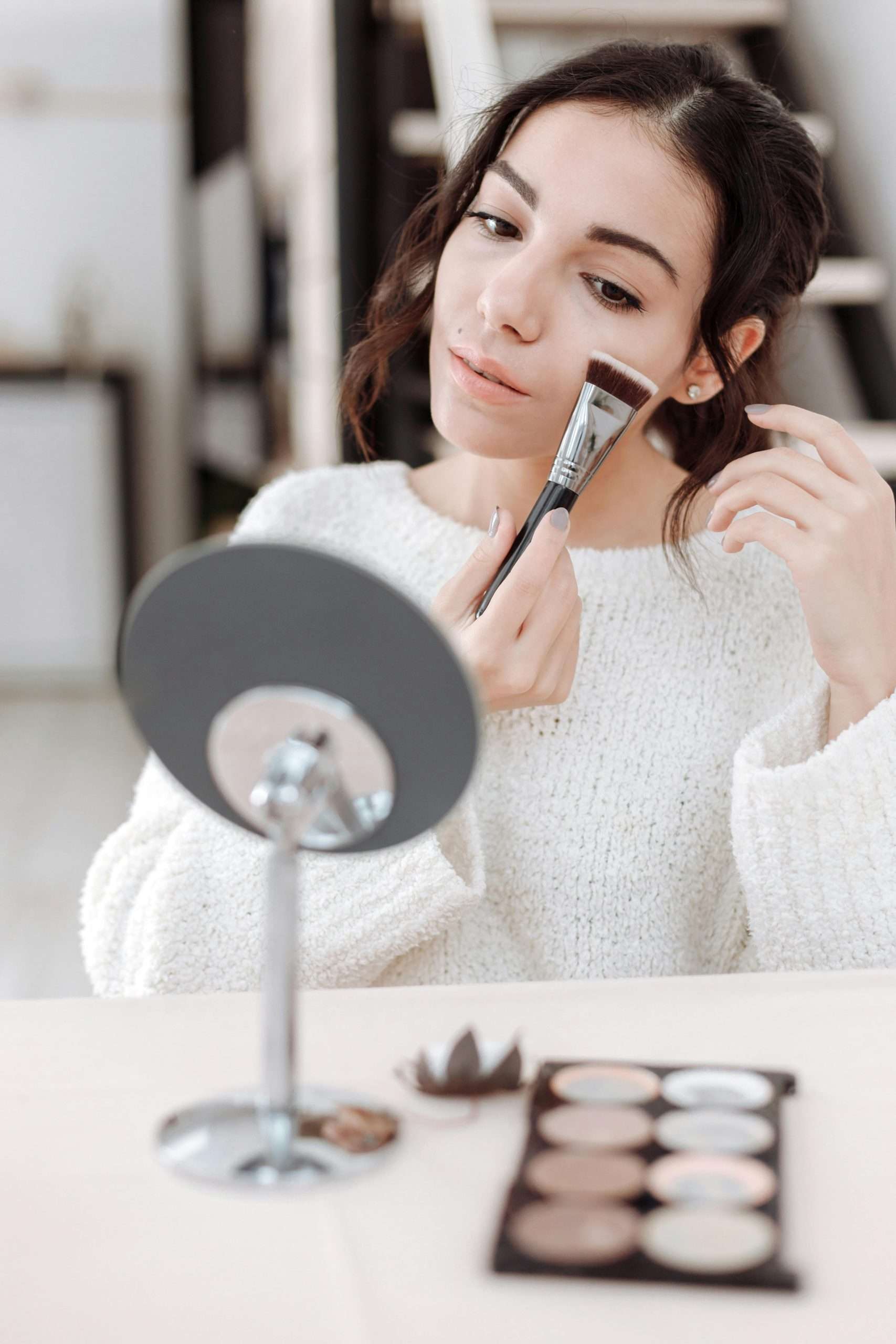 woman applying blush on her cheek