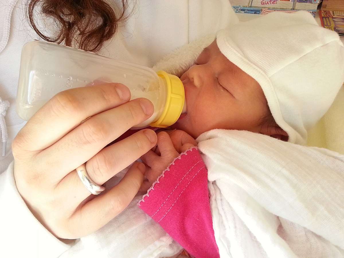 Newborn drinking milk from a bottle